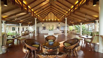 A spacious lobby with a high ceiling, wooden beams, and a central reception desk.