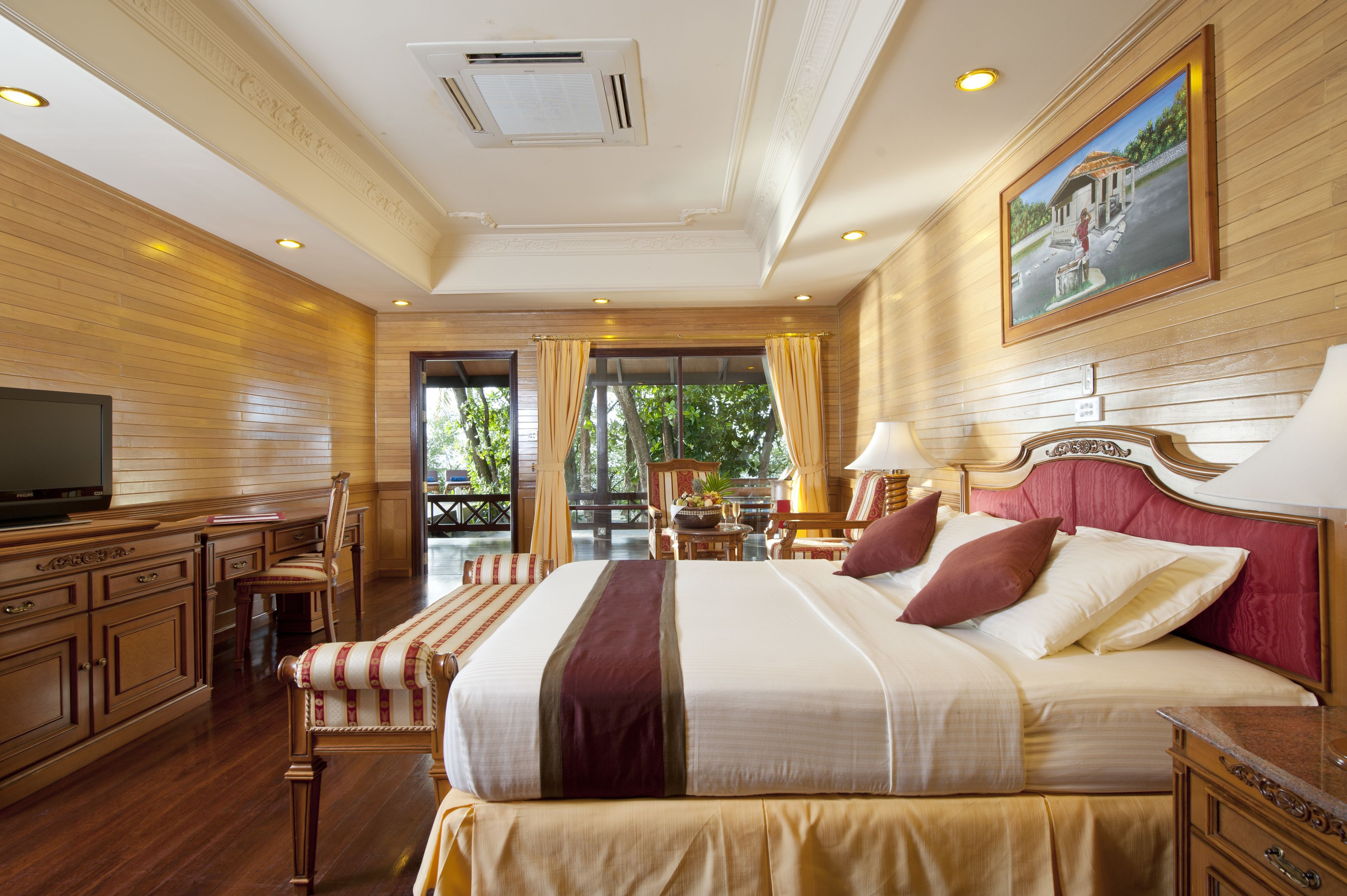 Un dormitorio espacioso con una cama grande, televisión, muebles de madera y vistas al balcón.