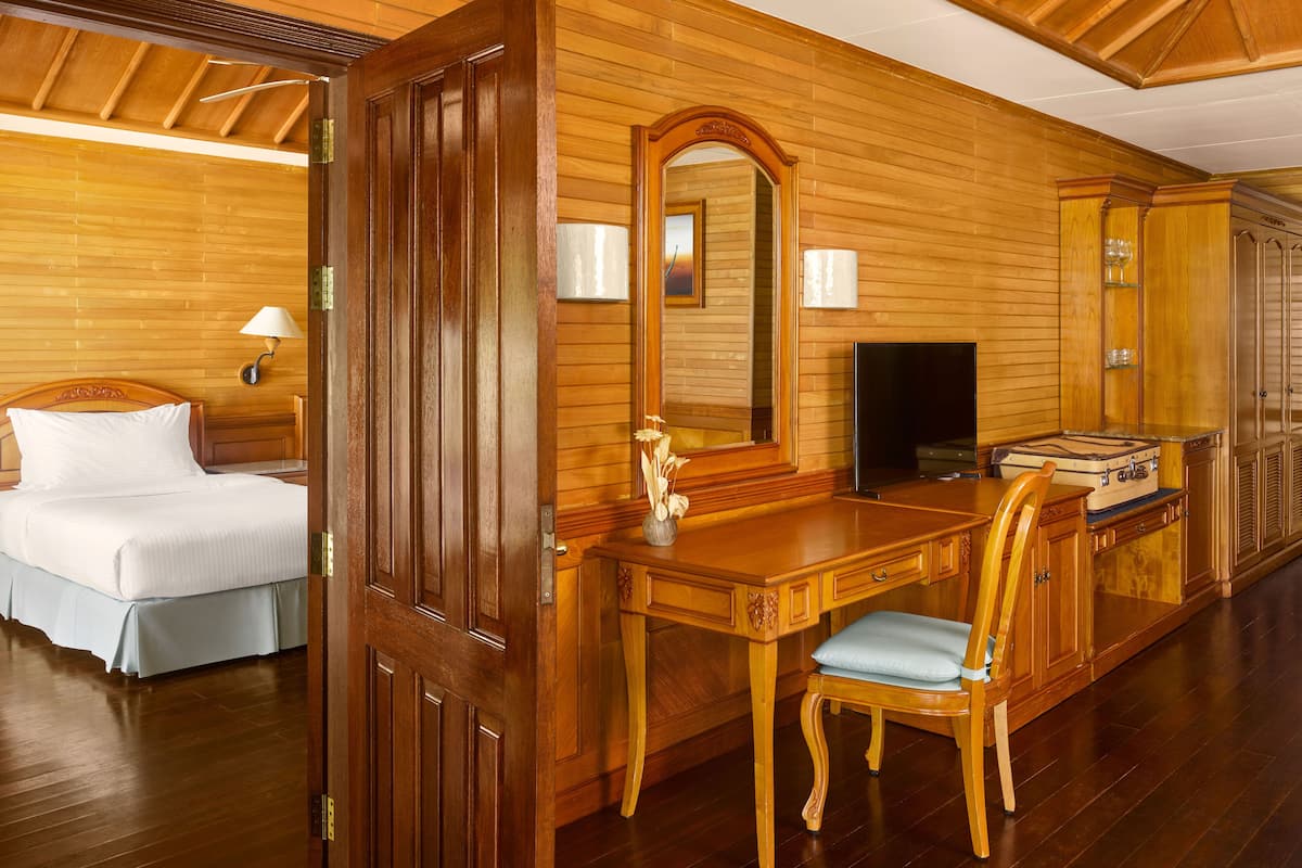 Ein Zimmer mit Holzausstattung, einem Bett, einem Schreibtisch mit Stuhl, einem Fernseher und einem Kamin.
