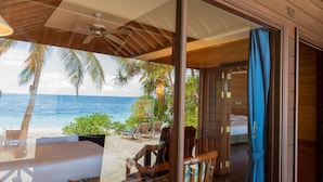 Habitación frente a la playa con vista al océano, muebles de madera y ventilador de techo.