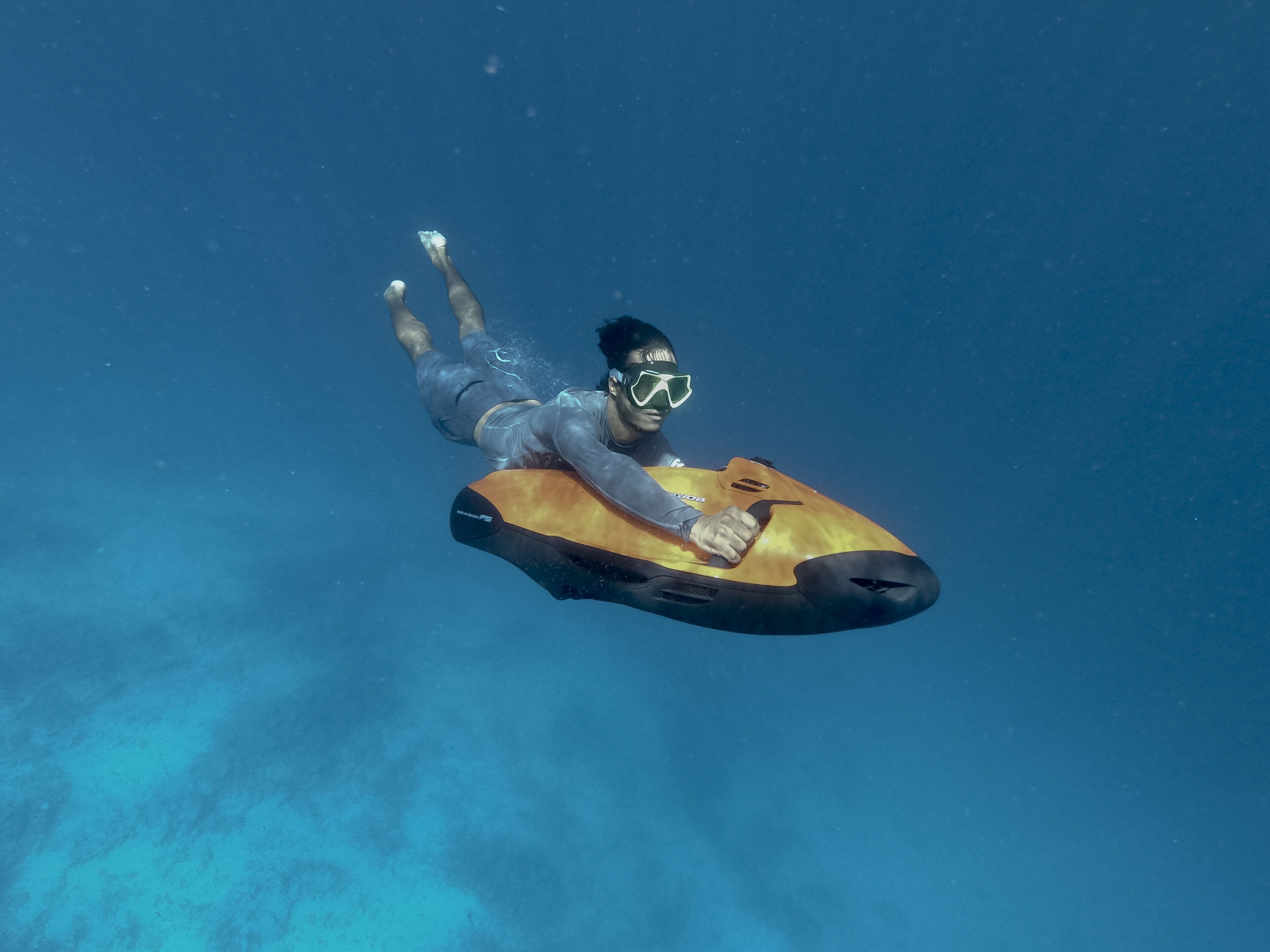 Eine Person unter Wasser auf einem gelb-schwarz gestreiften Brett.