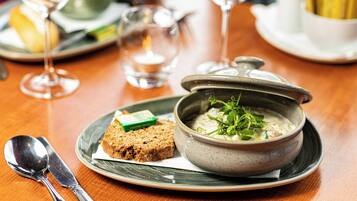 A dining table with a bowl of soup, a slice of bread, and a spoon.