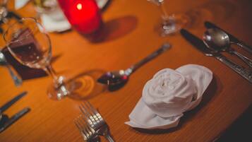 A dining table set with a white napkin, silverware, and a glass of red wine.