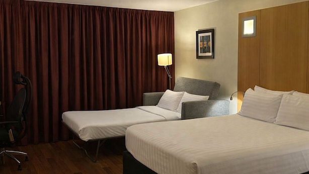 A hotel room with two single beds, a desk, a chair, a lamp, and a framed picture on the wall. - Station House Hotel (Letterkenny)