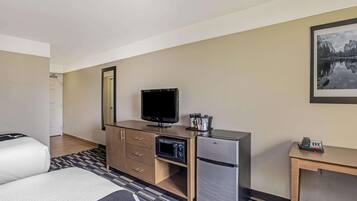 Habitación de hotel con cama, escritorio, televisor, refrigerador y microondas.