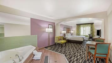 Ein Hotelzimmer mit einer großen Badewanne, einem Bett, einem Schreibtisch mit Stuhl und einem kleinen Tisch.