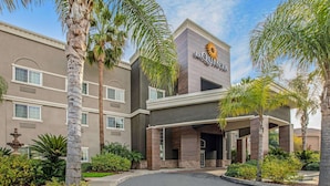 A hotel with a modern facade, palm trees, and a clear sky. - La Quinta Inn & Suites by Wyndham Modesto Salida (Salida)