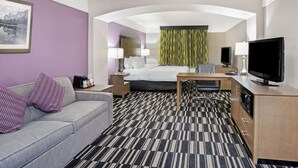 A hotel room with a bed, a sofa, a desk, a television, and a picture on the wall. - La Quinta Inn & Suites by Wyndham Modesto Salida (Salida)