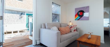 A living room with a sofa, a wooden coffee table, a ceiling fan, and a window with blinds.