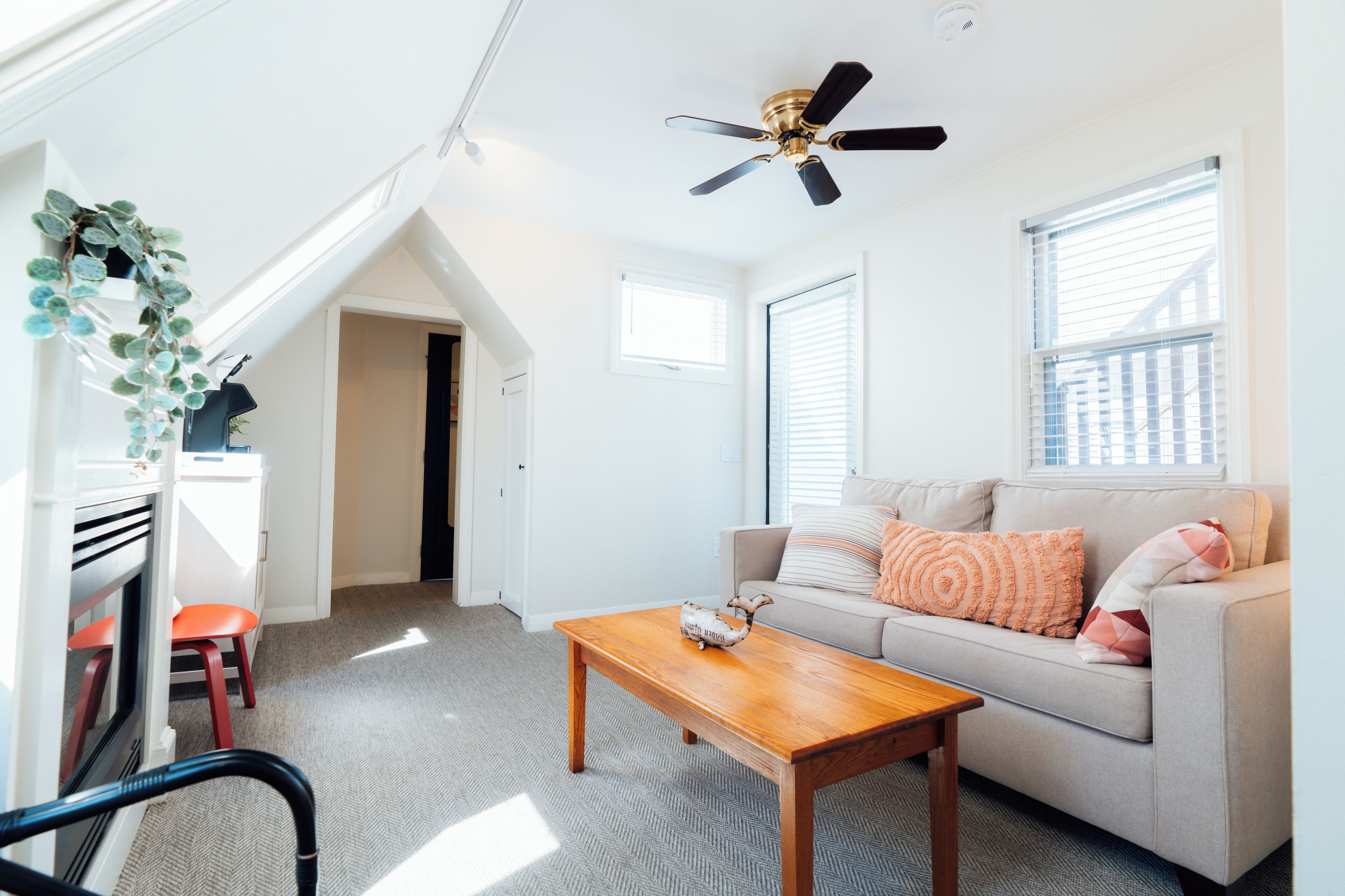 A bright living room with a sofa, a wooden coffee table, and a ceiling fan.
