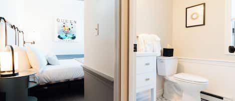 A hotel room with a bed, bedside table, and a poster on the wall.