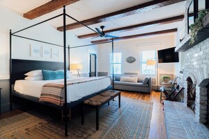 Un dormitorio con una cama con dosel, un banco, un sofá, una chimenea y un televisor.