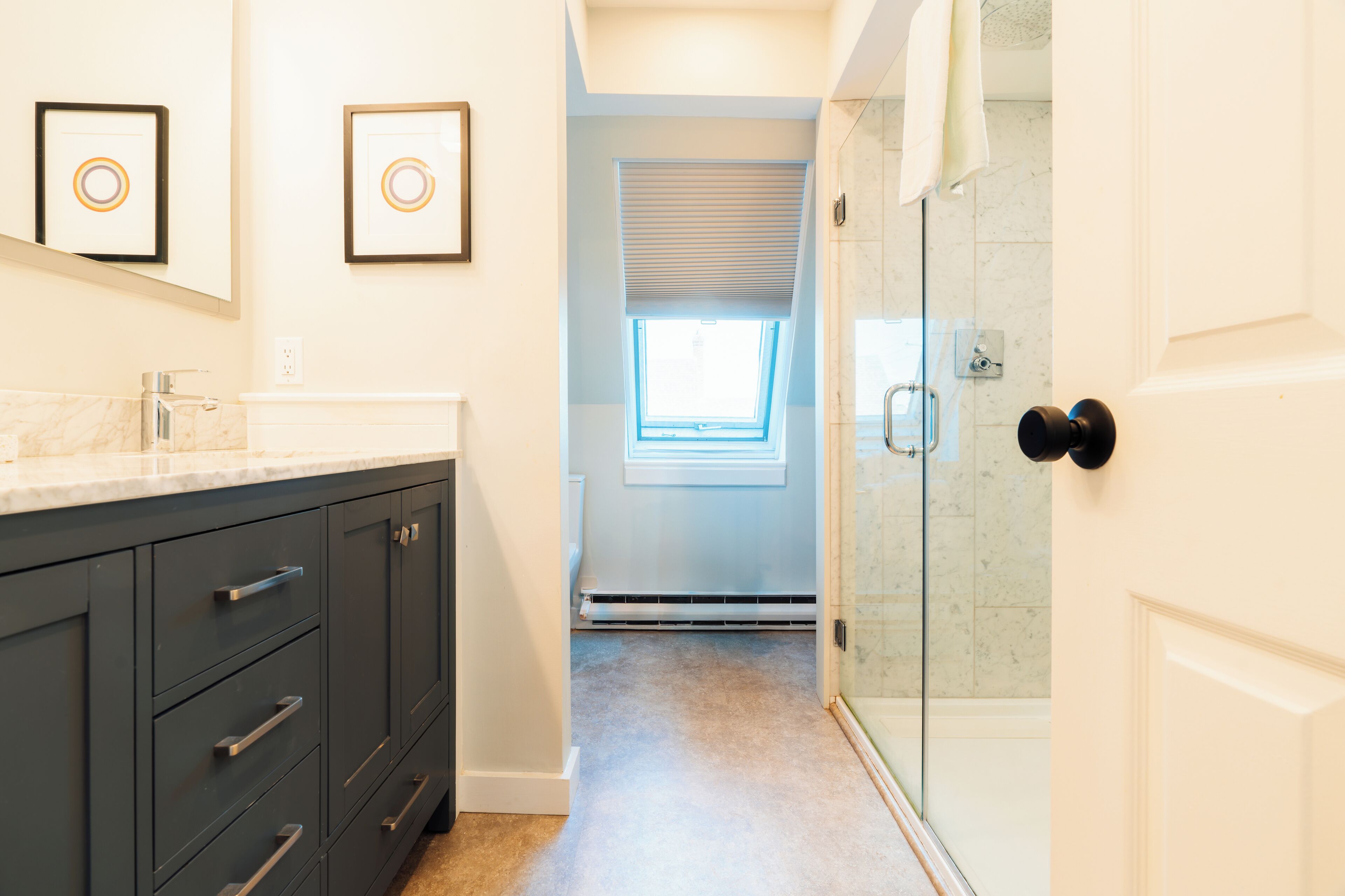 A modern bathroom with a large vanity, a glass shower enclosure, and a skylight.