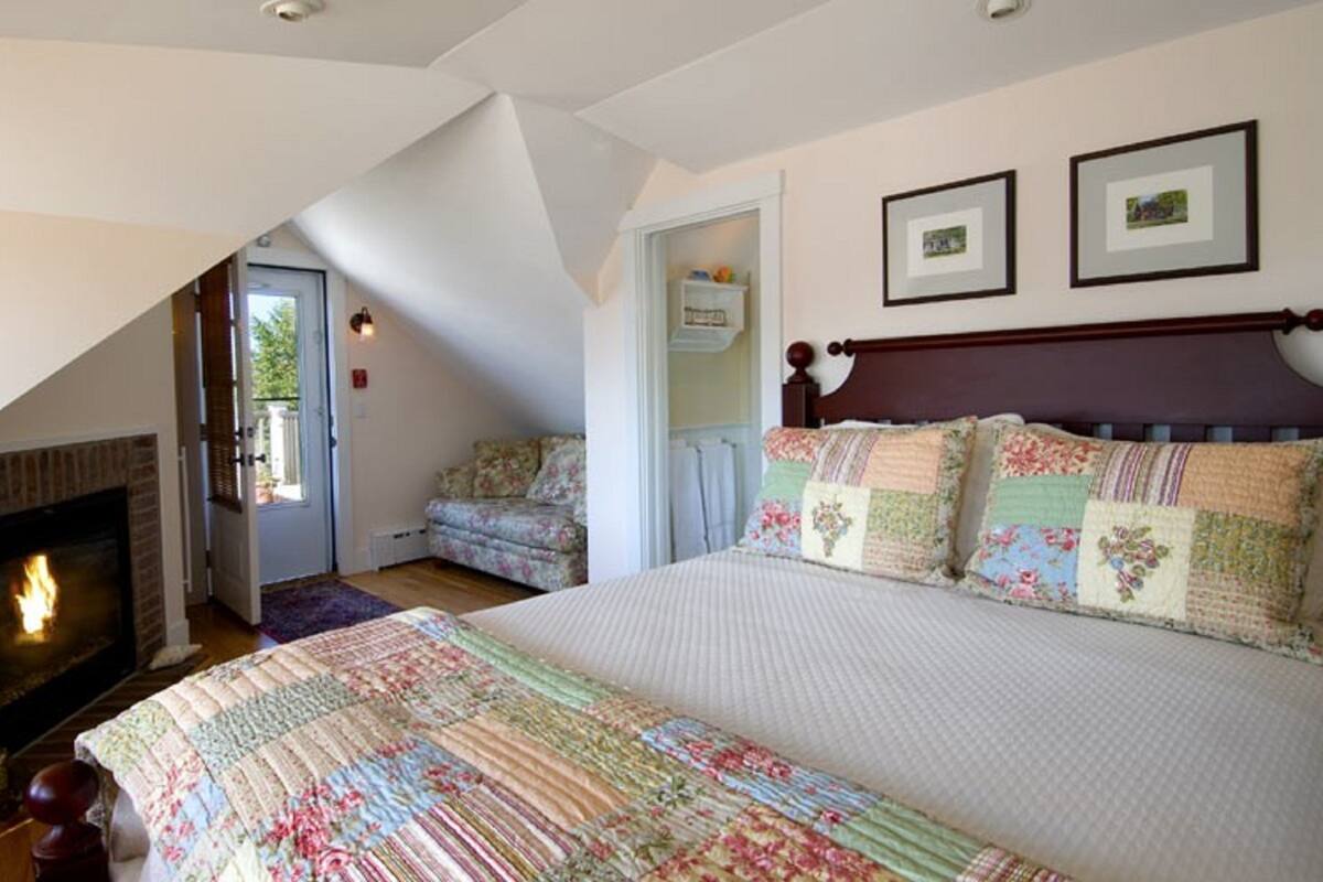 Ein Schlafzimmer mit einem großen Bett, einem Kamin und zwei gerahmten Bildern an der Wand.
