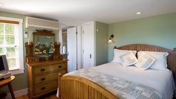 Une chambre à coucher avec un lit en bois, une commode, un miroir et une fenêtre avec des stores.