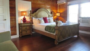 A room with a wooden bed, two bedside tables with lamps, a green chair, and a ceiling fan. - The Inn on Fleming (Key West)