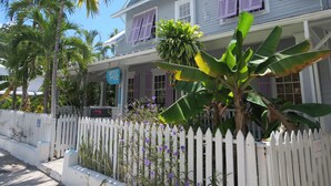 A two-story house with a porch, white picket fence, and a sign that reads "Artist House." - The Inn on Fleming (Key West)