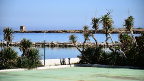 A pool area with palm trees and a view of the sea. - Palm Beach Hotel (Cinisi)