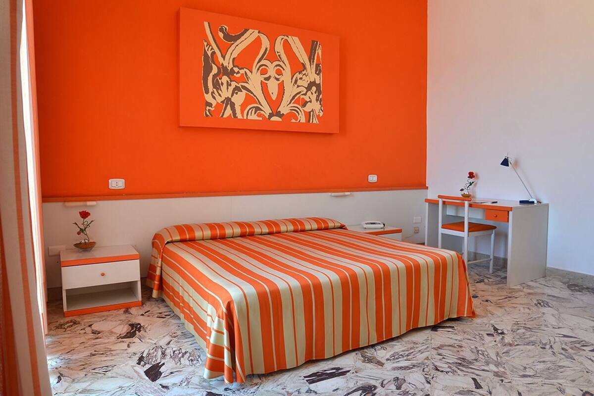 A bedroom with a bed, a desk, and a chair.