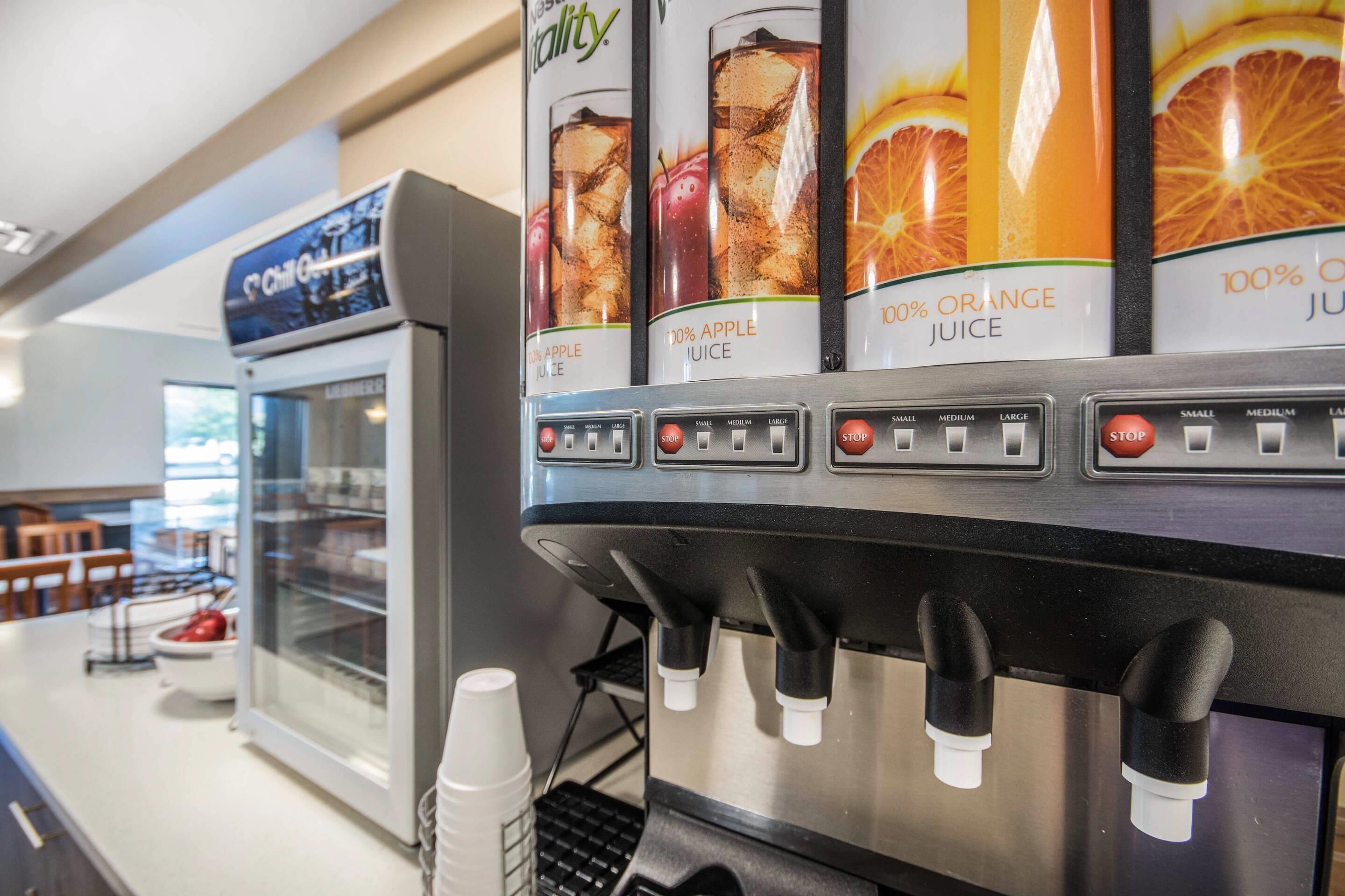 A juice dispenser with options for apple, orange, and 100% orange juice.