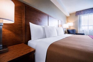 A hotel room with a large bed, a wooden headboard, a nightstand, and two bedside lamps. - Comfort Inn & Suites Langley - Fraser Highway (Langley)