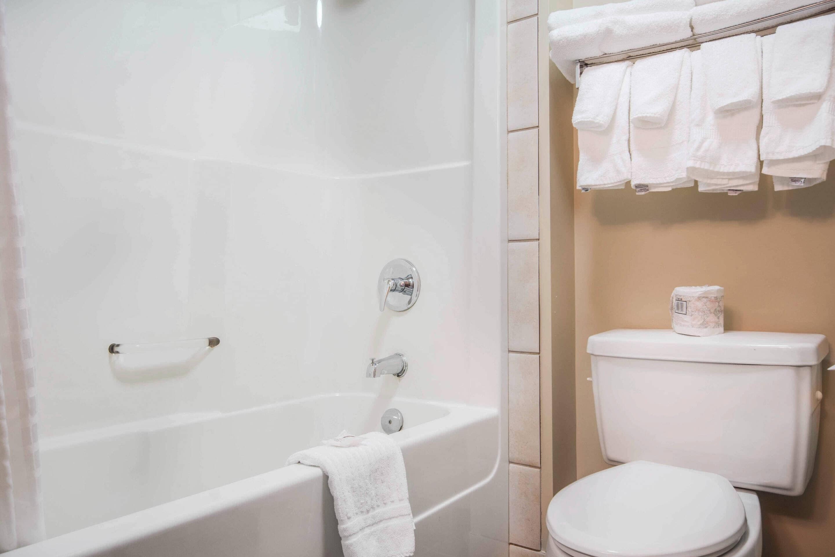 A bathroom with a bathtub, a toilet, and a towel rack with towels.