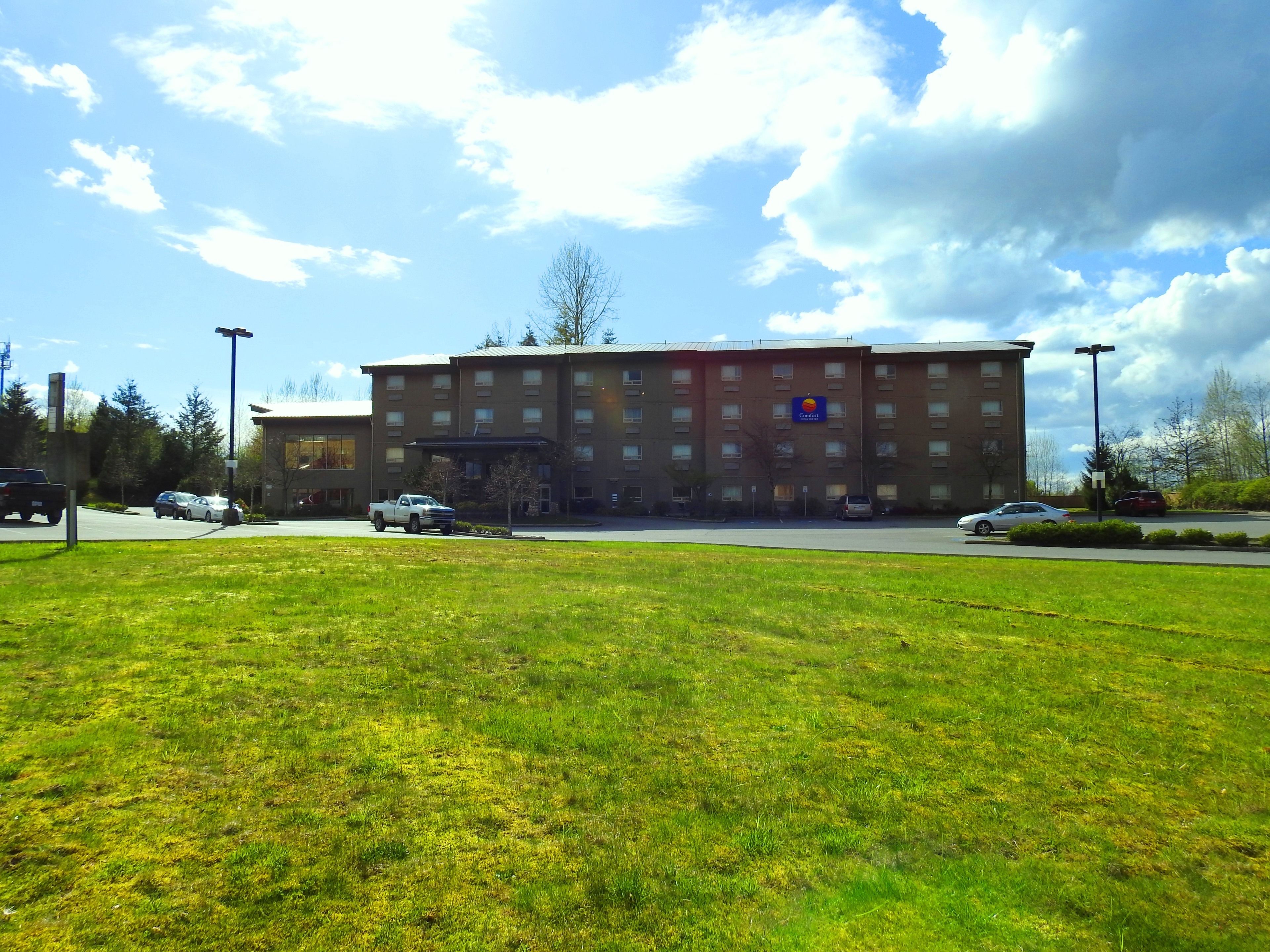A hotel with a parking lot and a grassy area in front.
