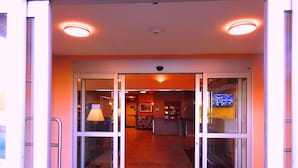 Ein Hotel Eingang mit Glastüren, einer Rezeption und einem gefliesten Boden.