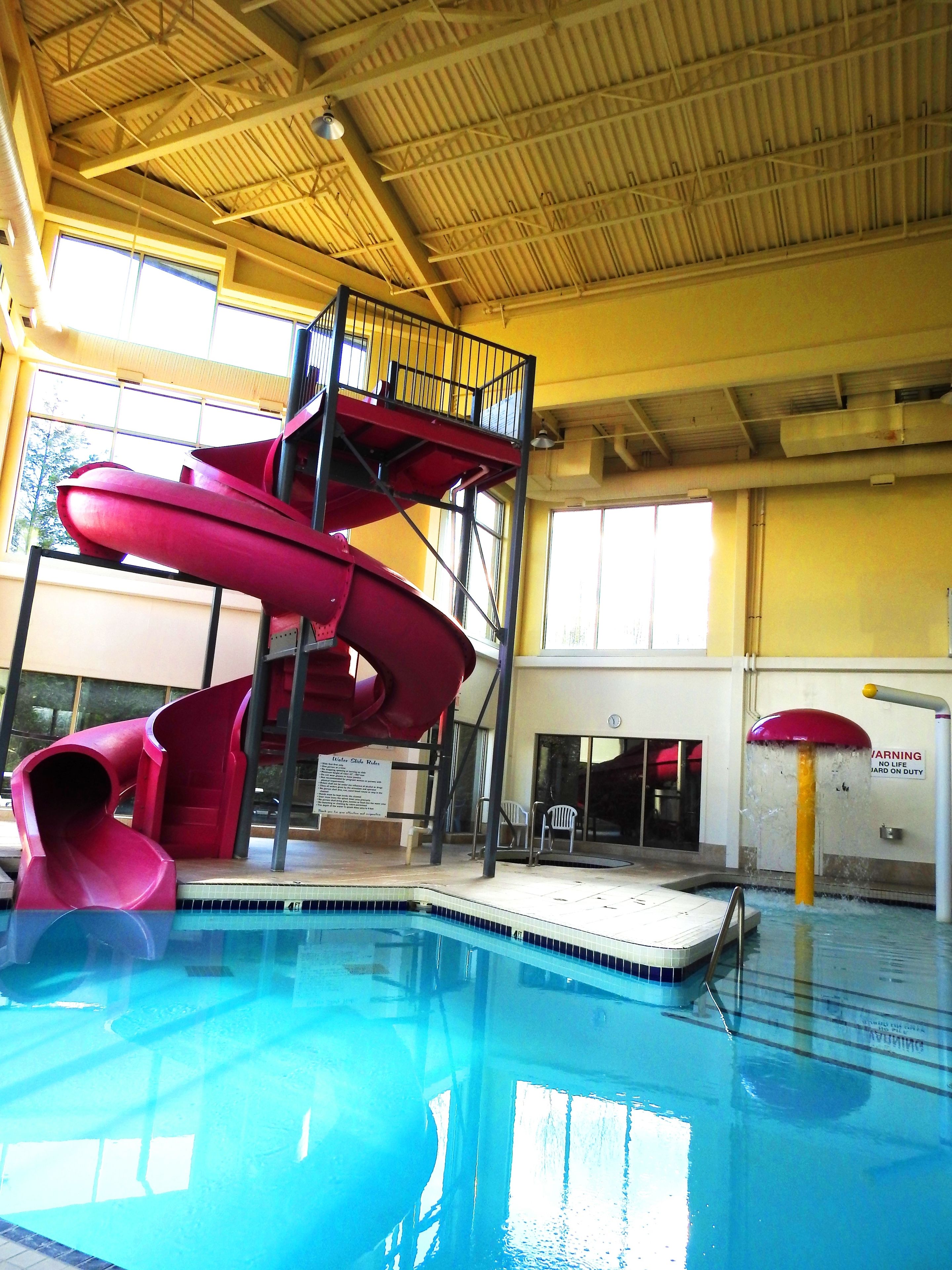 Ein Hallenbad mit einer roten Rutsche und einem Rettungsschwimmerstand.