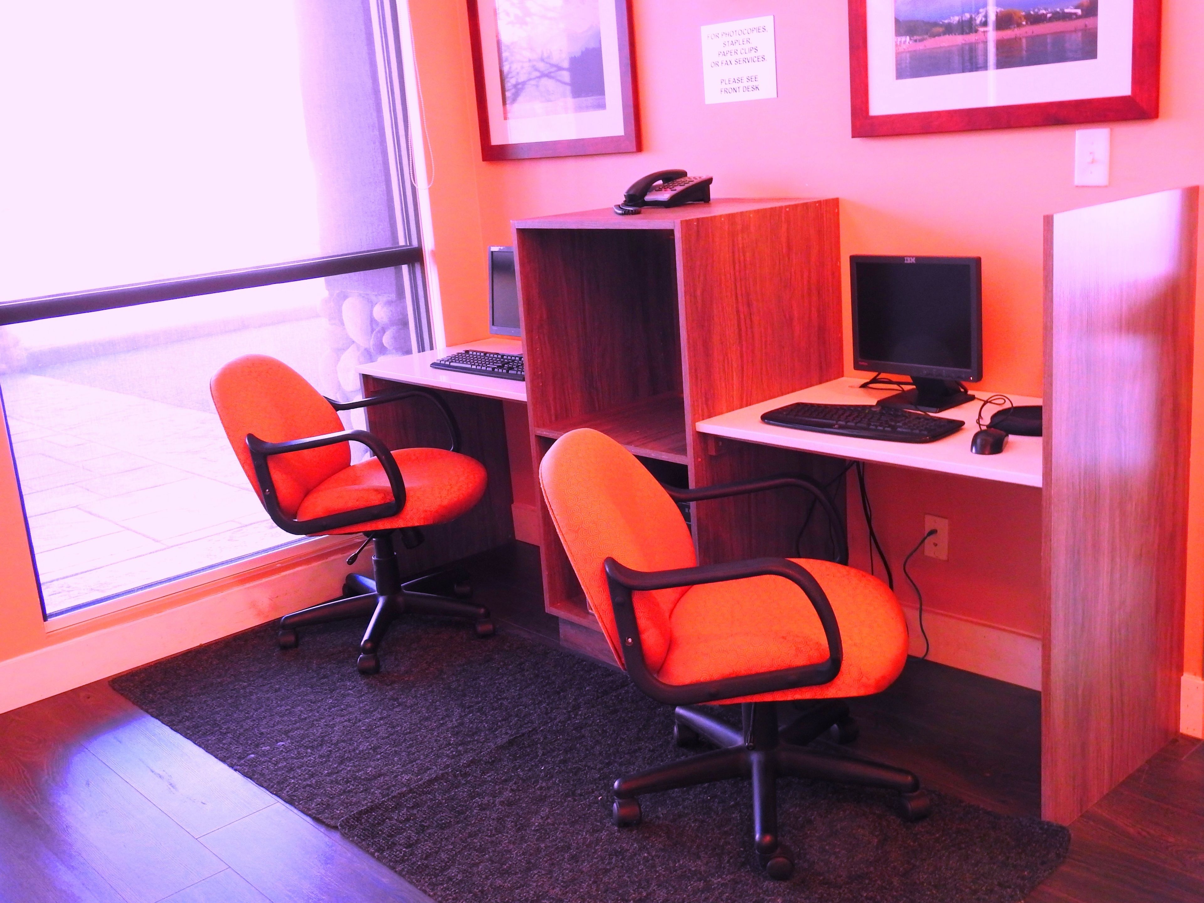 A workspace with two orange office chairs, a desk with a computer, and a phone.