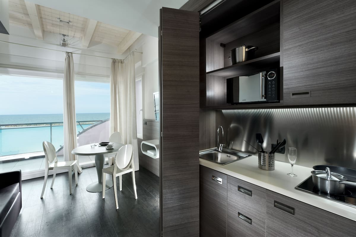 A modern kitchen with a built-in microwave, stainless steel sink, and a dining area with a view of the ocean.