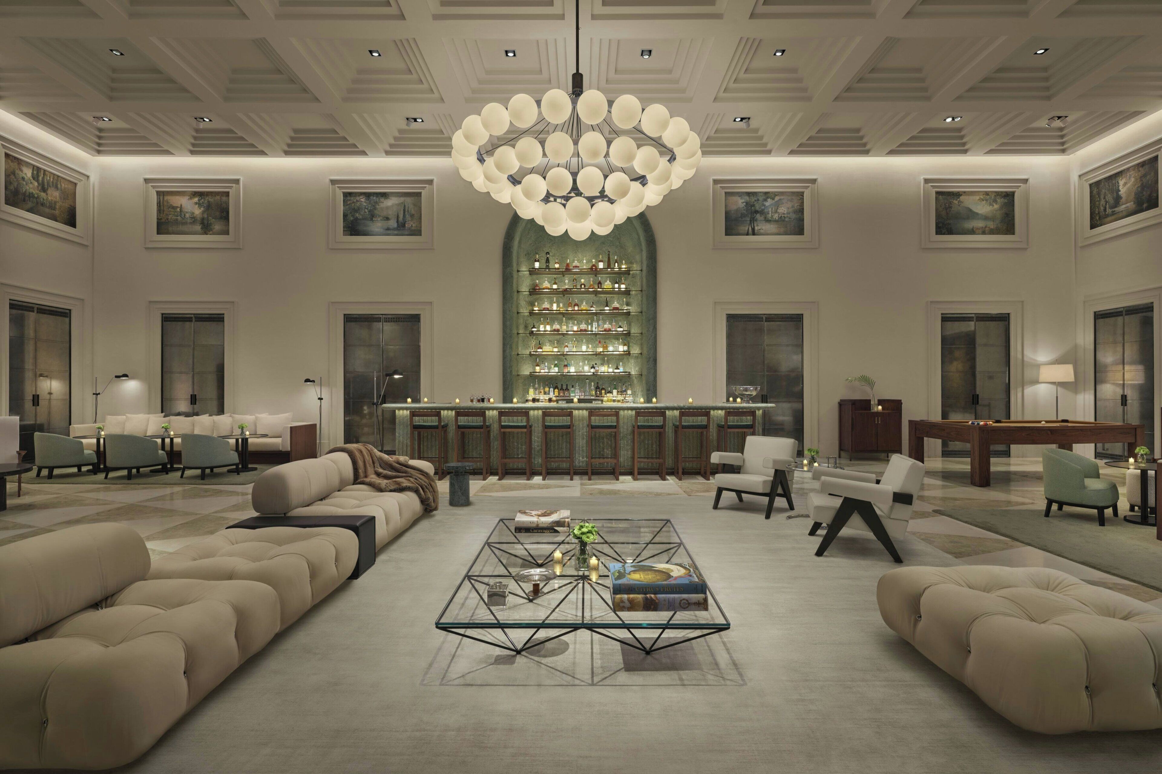 A spacious lobby with a central bar, comfortable seating, and a large chandelier.