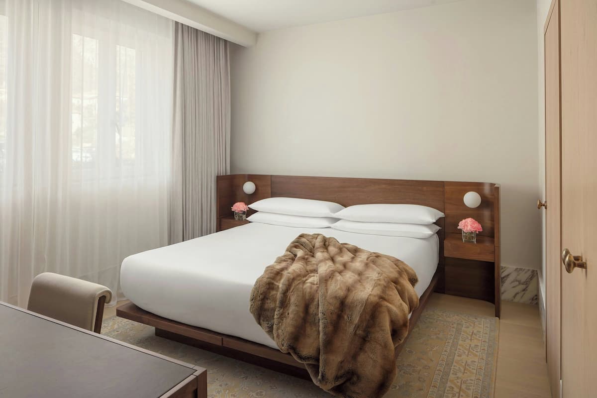 A hotel room with a bed, a desk, and a chair.