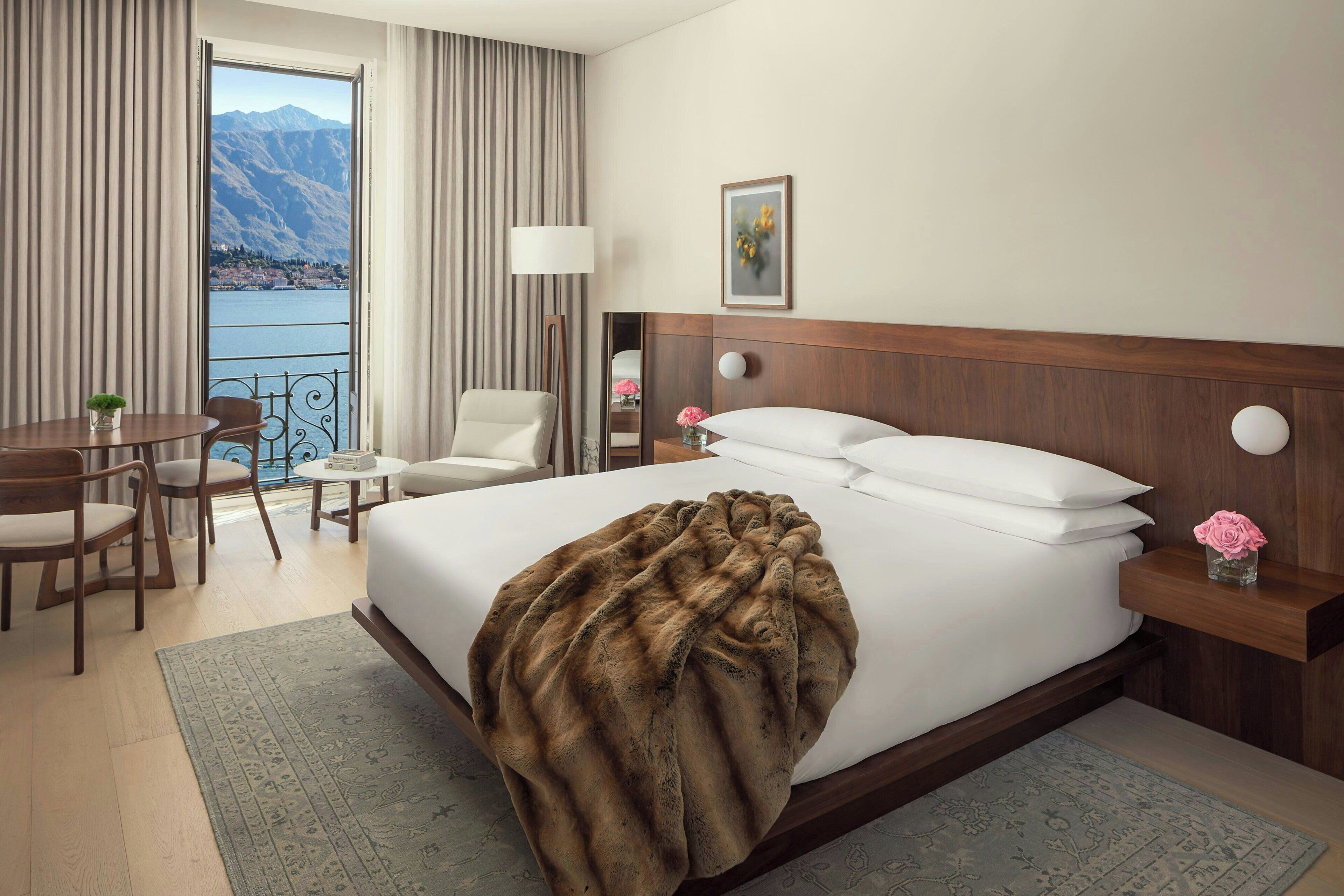 Une chambre d’hôtel avec un grand lit, un bureau, une chaise et une vue sur les montagnes depuis un balcon.