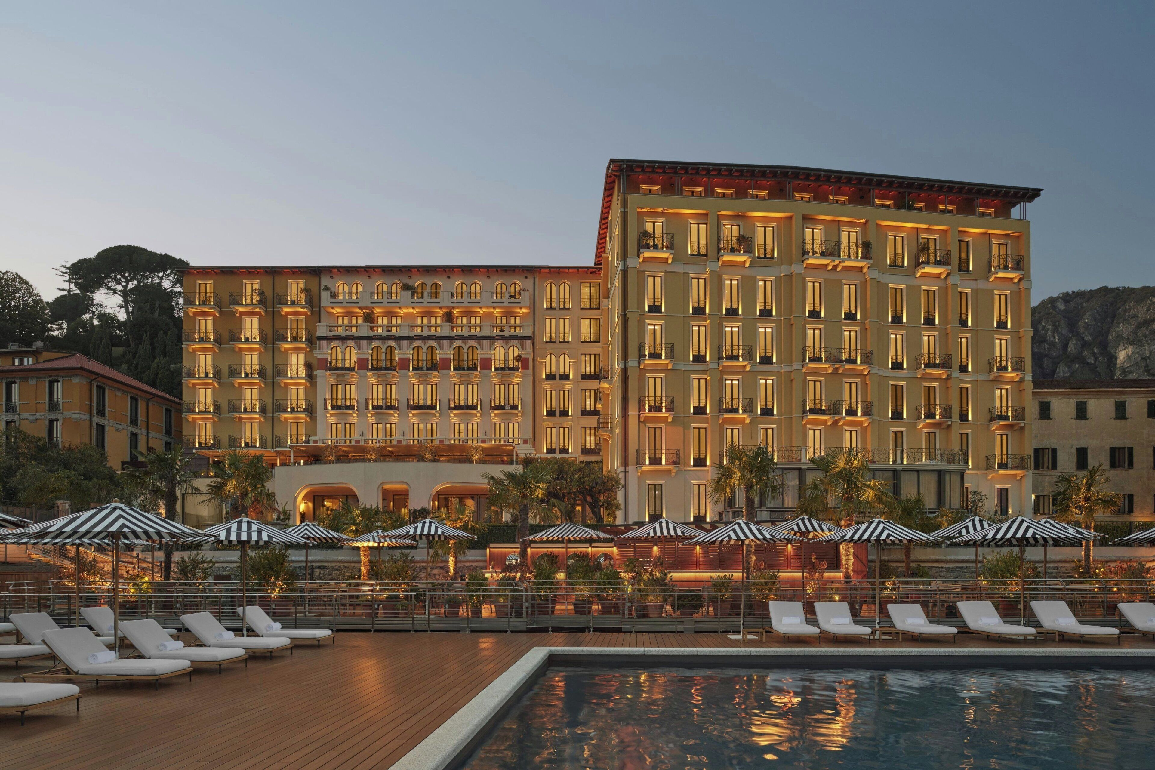Un hotel con numerosi balconi, una piscina e lettini prendisole.