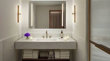 A modern bathroom with a large mirror, two sinks, and a vanity with towels.