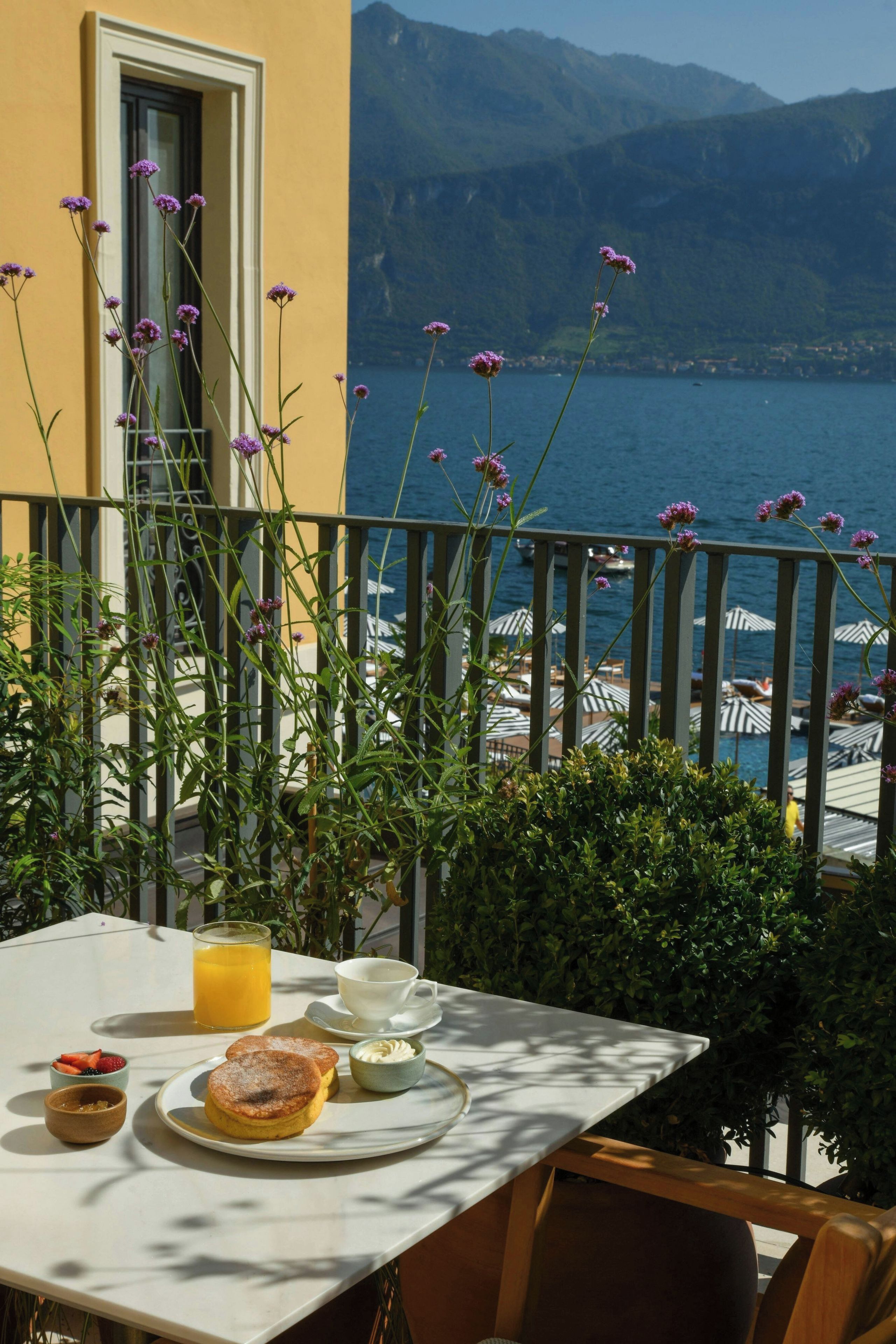 A table set with breakfast items, overlooking a coastal view with mountains in the background.