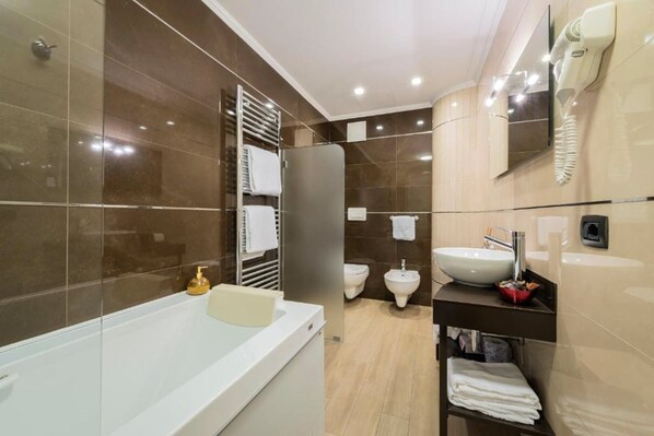 Un baño moderno con una bañera grande, un tocador con lavabo, un bidé y un perchero para toallas.