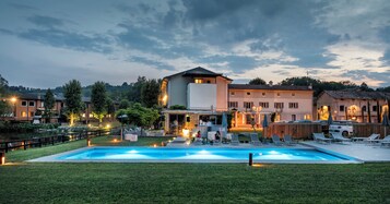 A swimming pool with lounge chairs and a deck area, surrounded by a well-maintained lawn and a building with multiple windows and a balcony.