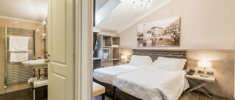 A hotel room with a large bed, a bedside table with a lamp, a bathroom with a towel rack, and a cityscape painting on the wall.