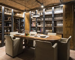 A restaurant with a wooden table and chairs, surrounded by shelves of bottles.