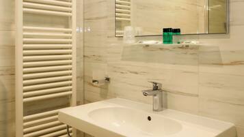 Un baño moderno con un lavamanos blanco, un espejo y un perchero para toallas.