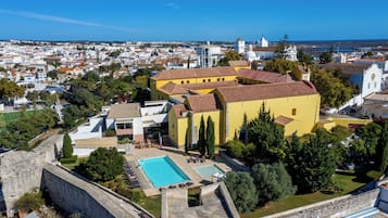 A yellow building with a swimming pool and a view of the city.