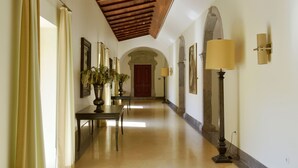 A hallway with a wooden ceiling, a table with a vase, and a lamp.