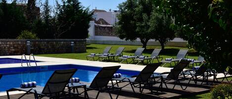 Un área de piscina con sillas de descanso y un muro de piedra.