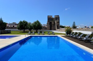 Una piscina al aire libre, sillones reclinables de piscina