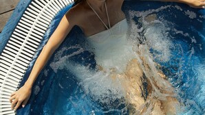 A person relaxing in a hot tub with a straw hat, surrounded by a wooden deck. - Hotel JS Paradise Sport - Adults Only (Llucmajor)