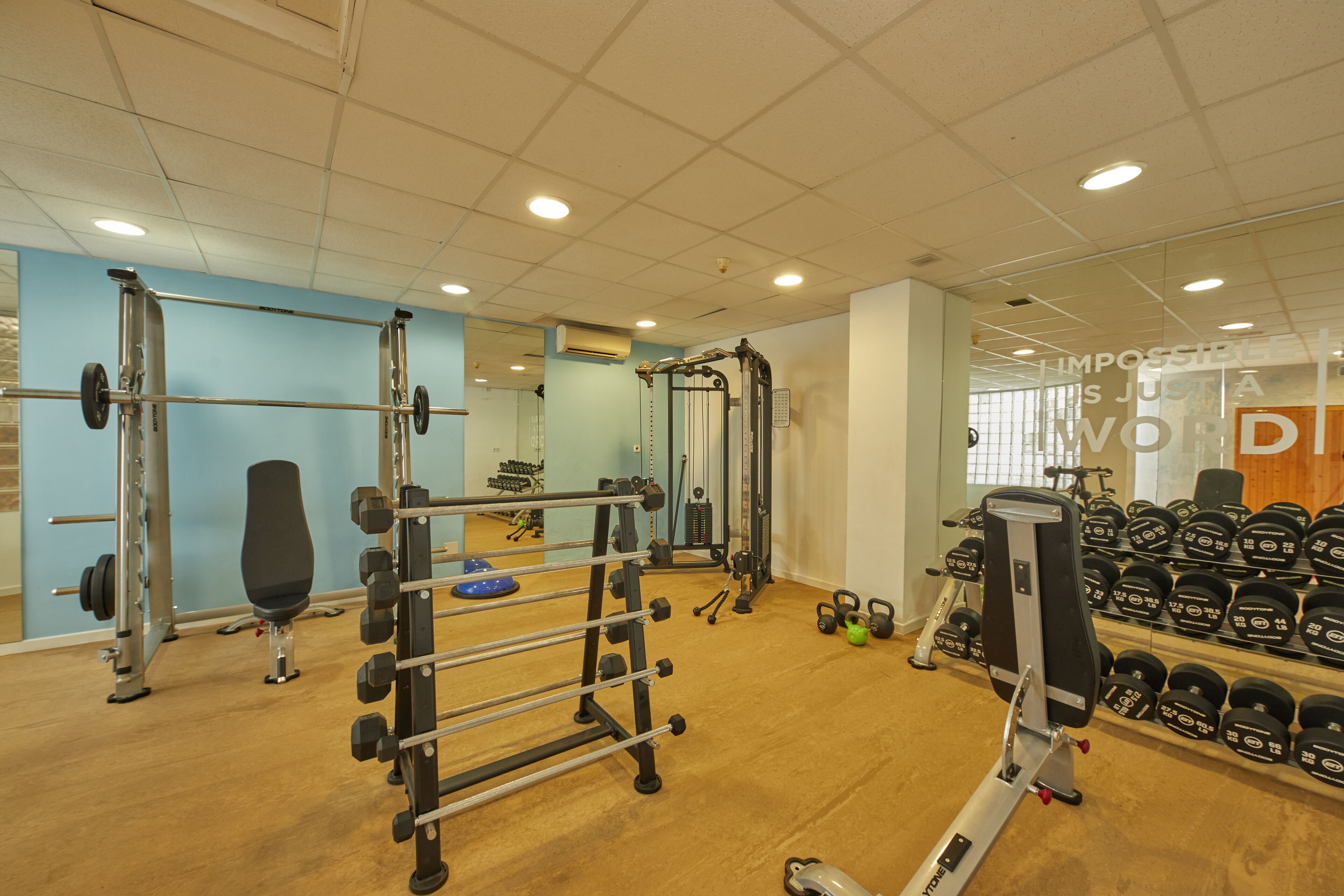 A gym with weightlifting equipment, a bench, and a rack of dumbbells.