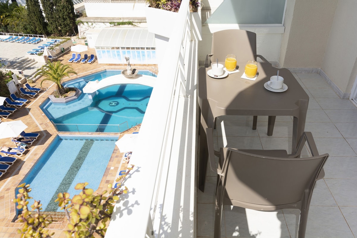 Un área junto a la piscina con mesa y sillas, una piscina pequeña y sillones de descanso.