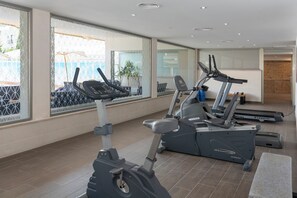 Un gimnasio con bicicletas estáticas, cintas de correr y un espejo grande.